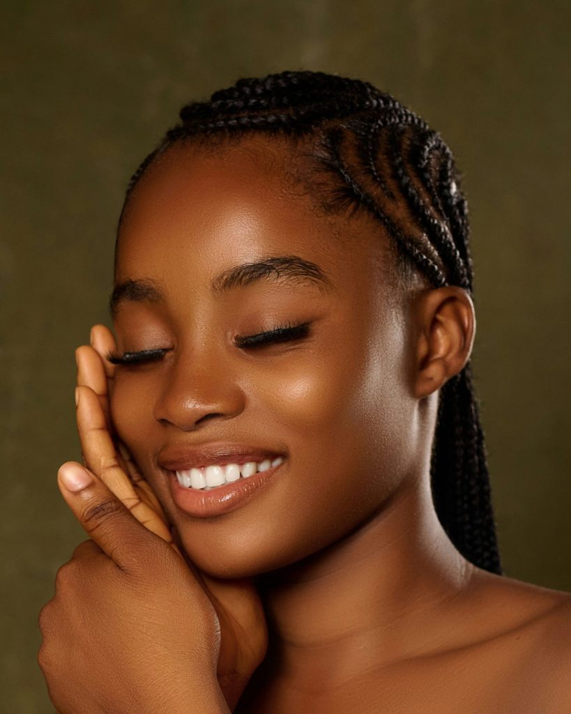 Smiling young woman with braided hair and closed eyes.